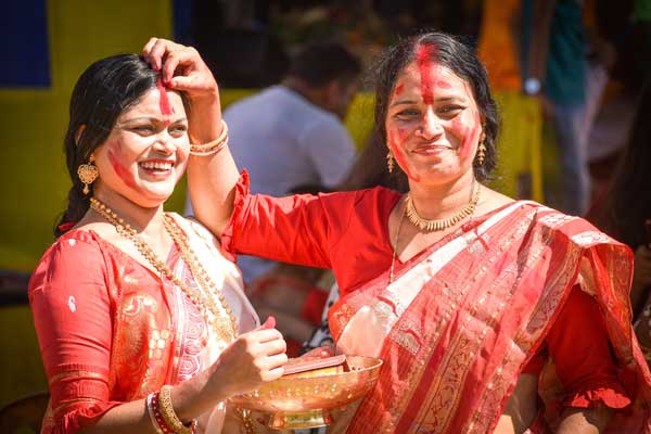 Two Indian females wearing sari's apply bindi's on each others forhead