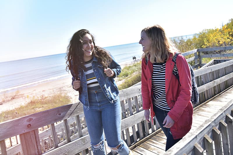 Two students walking outdoors along Lake Michigan boardwalk