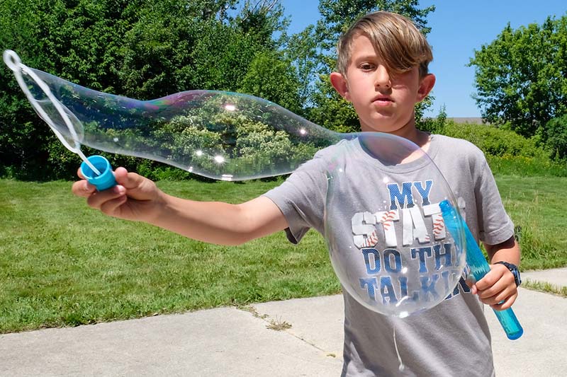 young teen outside with bubble wand