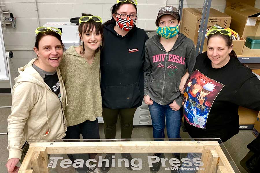 Students pose for photo with Professor Rebecca Meacham by Teaching Press Equipment