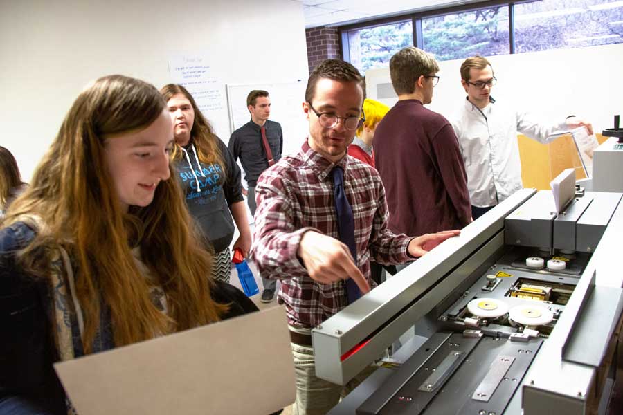 Professor shows student equipment at Teaching Press open house