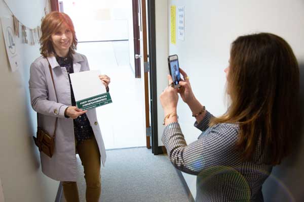 Professor Rebecca Meacham takes photo of guest at The Teaching Press open house