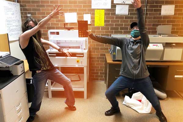 Student strike a silly pose in front of Teaching Press equipment