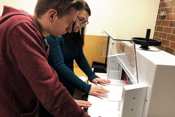 Students work with Teaching Press Equipment to bind book