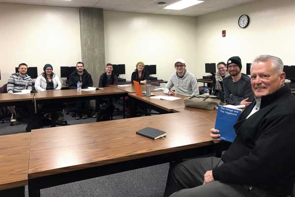 Tim Weyenberg holds up book with posing with Teaching Press students