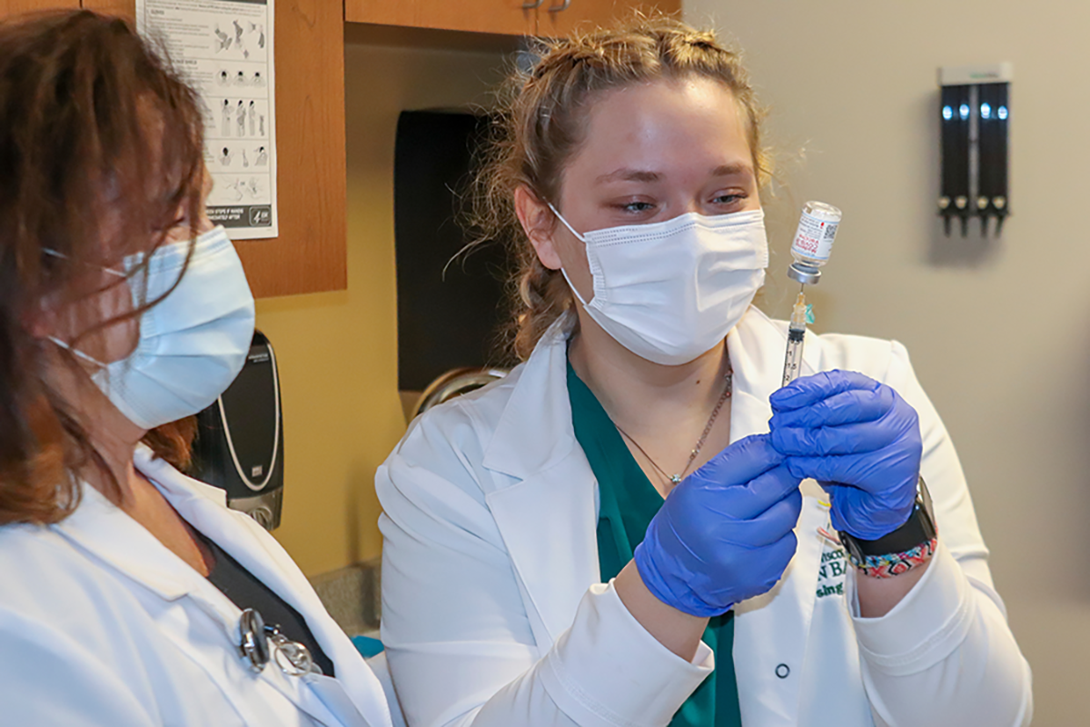 UW-Green Bay nursing student administers COVID-19 vaccine while an instructor observes.