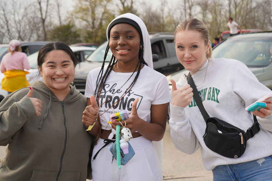 Three students signal thumbs up and smile for photo