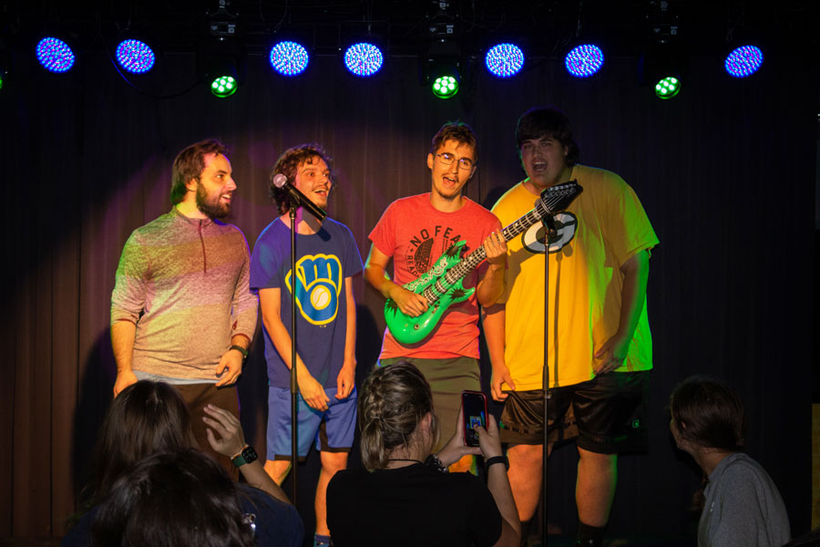 Four male students singing on stage at Phoniex Club