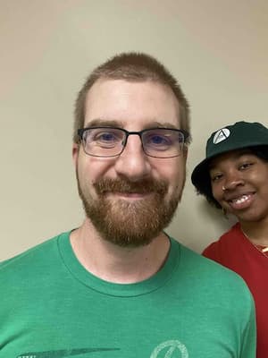 Male posing for headshot with friend in background