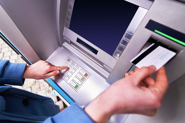 Person inserting debit card into ATM