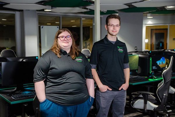 Photo of Esports co-managers posing in front of the gaming PCs in the Esports lounge