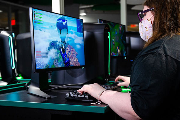 Female student playing computer game in E-sports lounge