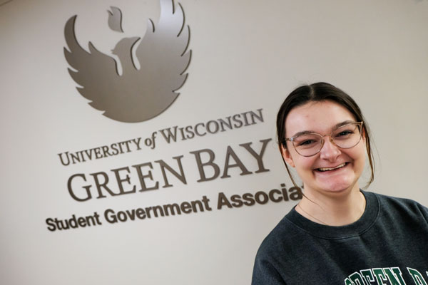 Student poses in front of Student Government Association sign