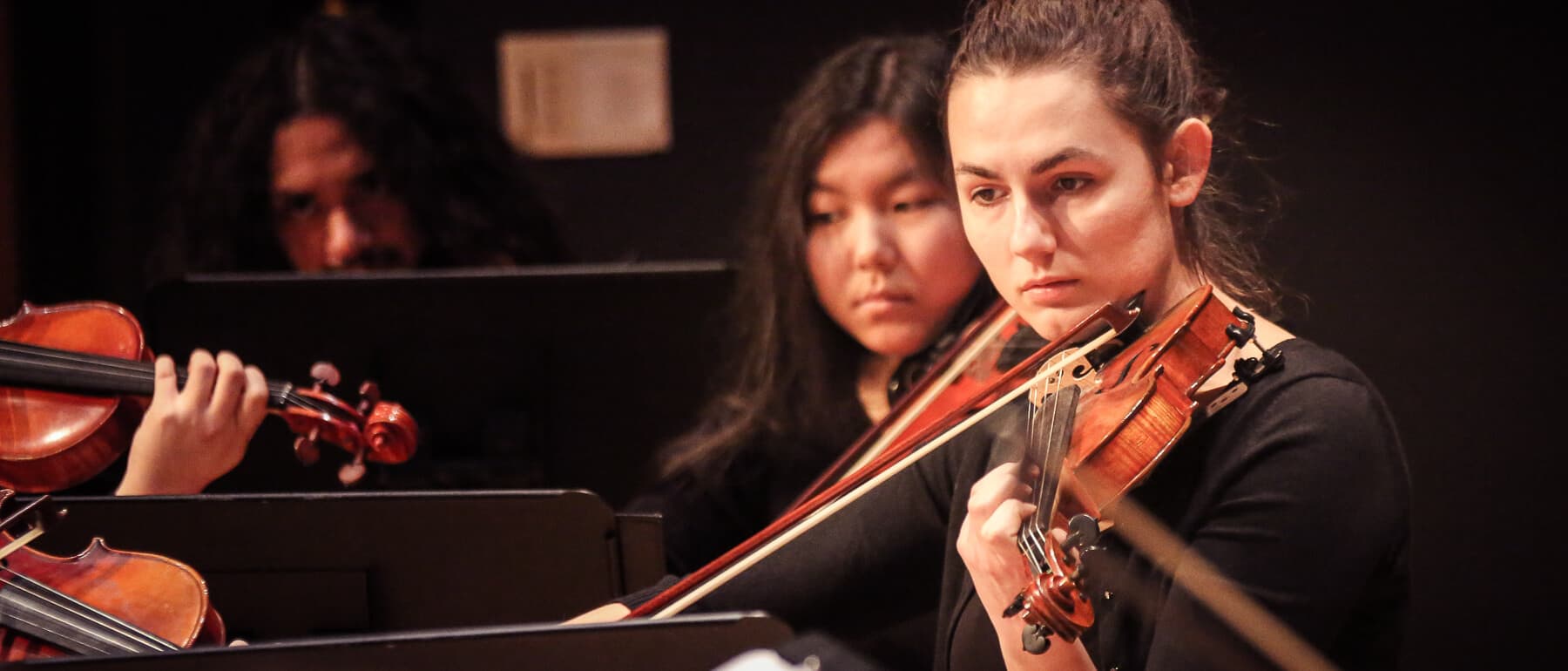 UWGB students perform in an orchestra on stage.