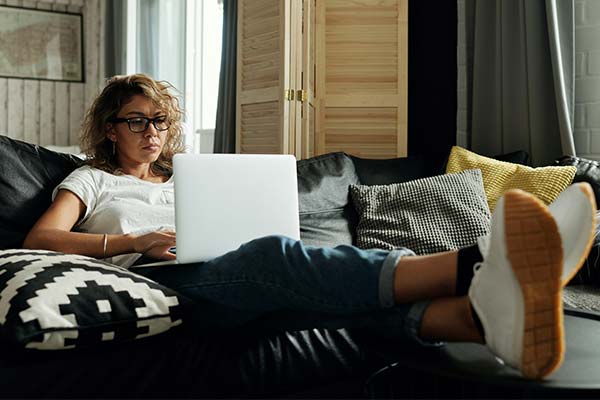 Woman working on her laptop in her living room with her feet up