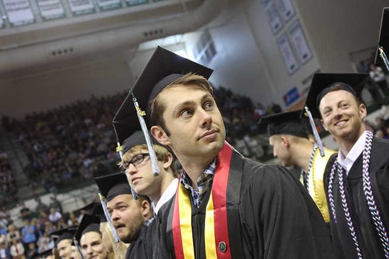 A UWGB student looks over his shoulder at graduation.