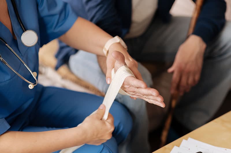 Caregiver wrapping patients hand with gauze