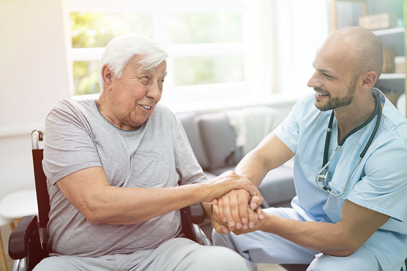 Caregiver holding elderly patients hands