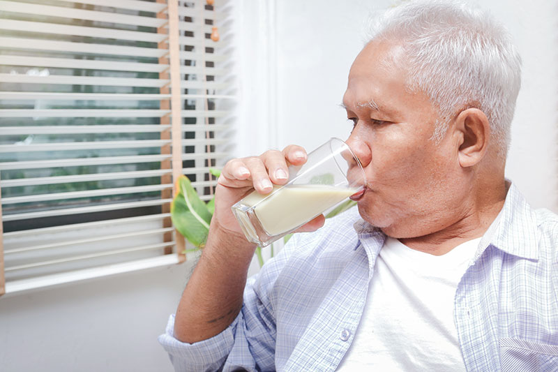 Elderly man drinking milk containing calcium