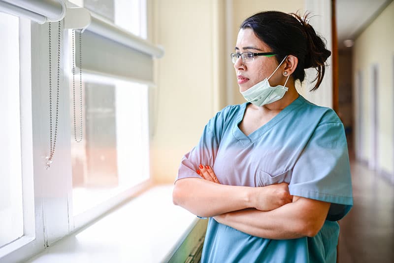 Nurse looking out window with arms crossed