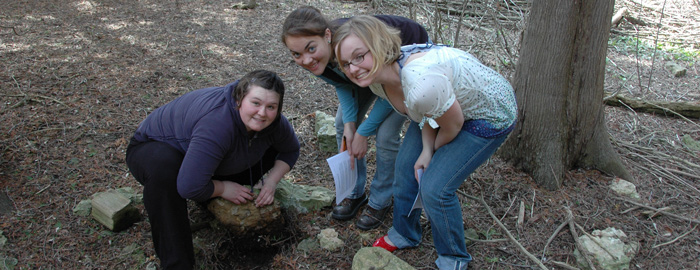 ecology students look for salamanders under rocks on the Cofrin arboretum.