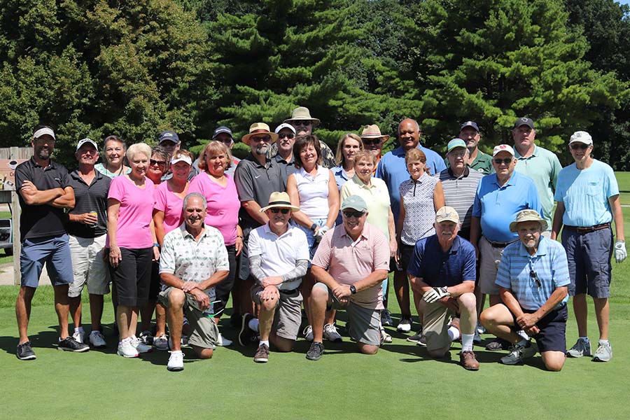 A large group of people posing at a golf course