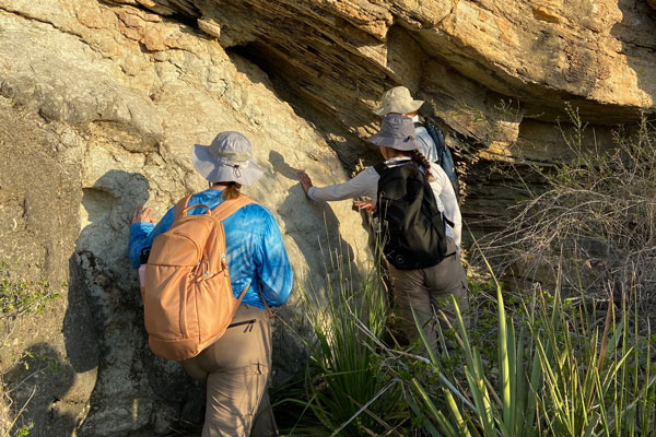Students hike large rock formation