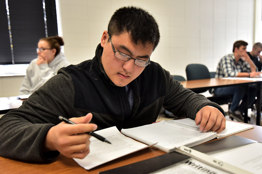 Student writing in a notebook in a classroom