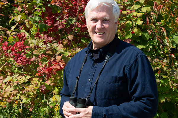Bob Howe with binoculars, outdoors