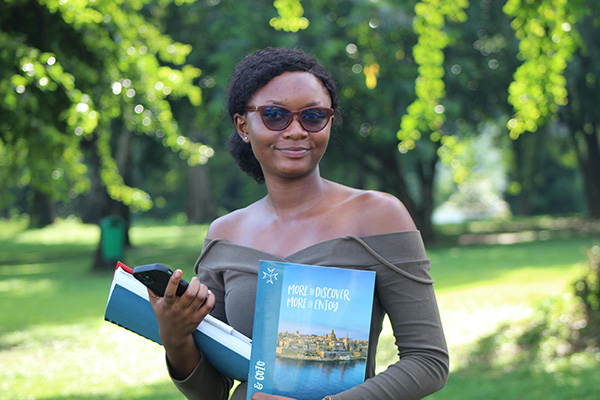 Woman outdoors, holding textbooks and travel book