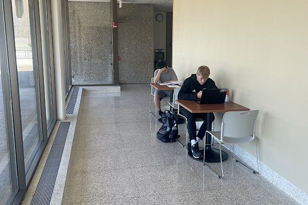 Two students at tables in hall study area