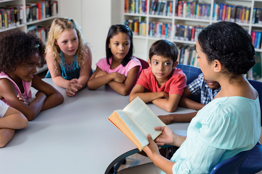 A woman reads to children at a table