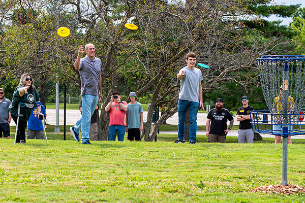 Students and chancellor playing disc golf