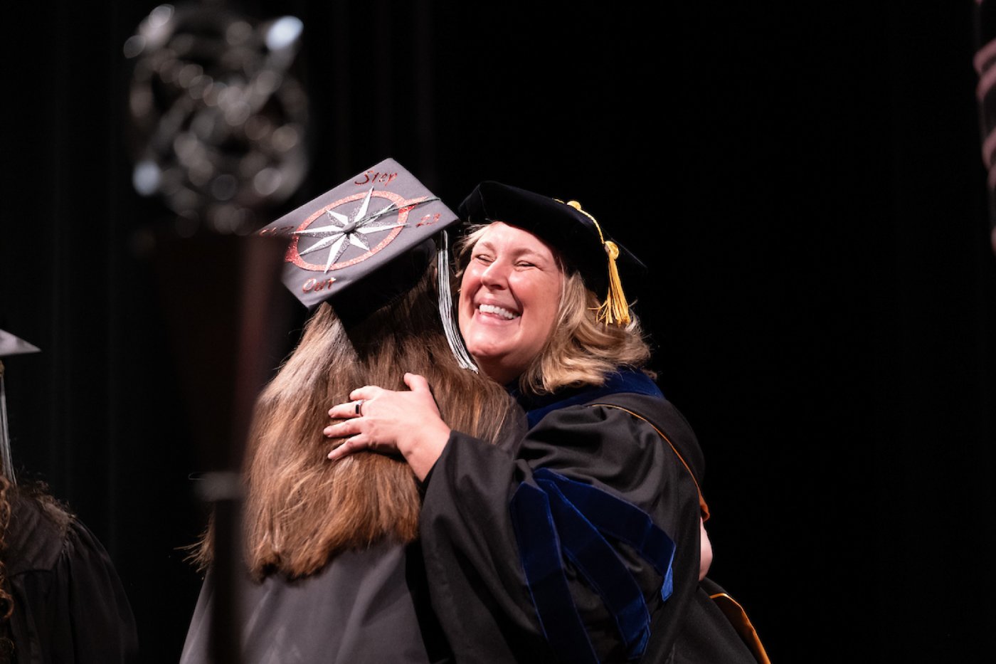 A faculty member embraced a student on the commencement stage