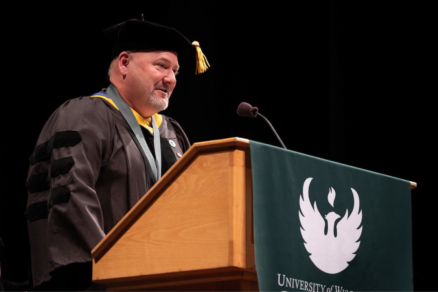 A faculty member addresses the audience at the commencement lectern