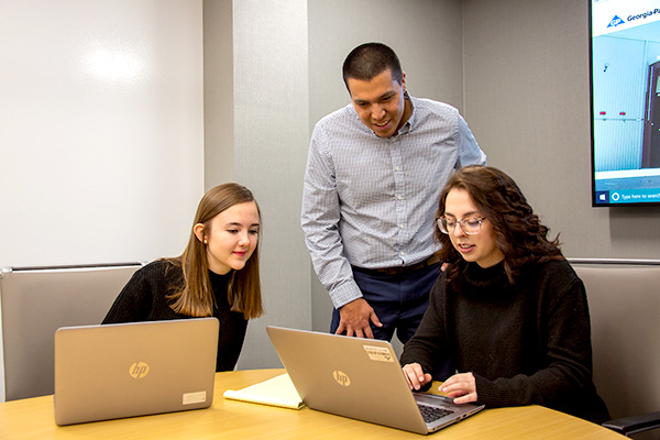 Interns working on laptops with mentor