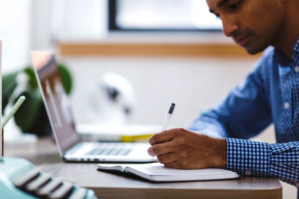 Student taking notes during online class