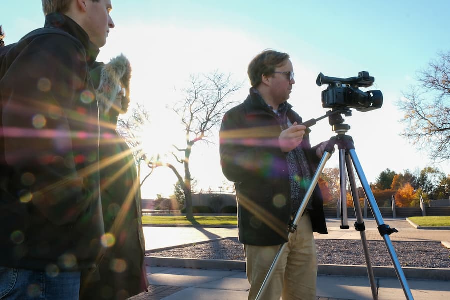 A videographer setting up a scene to record on campus.