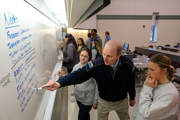 Students work with professor Phil Clampitt during Social Media Strategies Class