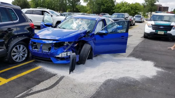 Blue sedan with a crumpled front, bent axil and shattered windshield after a crash