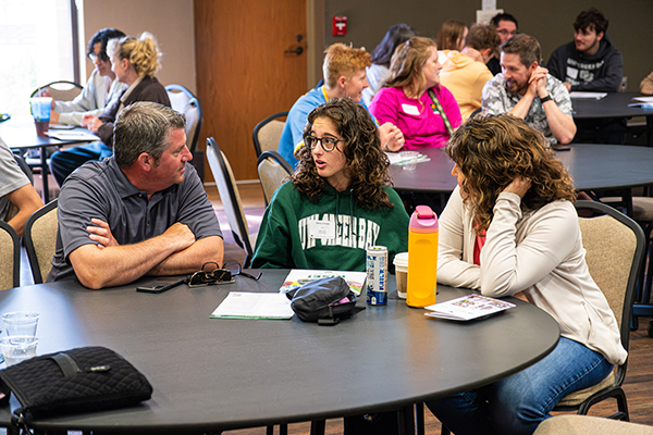 A family sits together at a round table and talks during GB Orientation