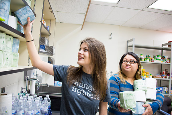 Students re-stocking toilet paper on shelter shelves