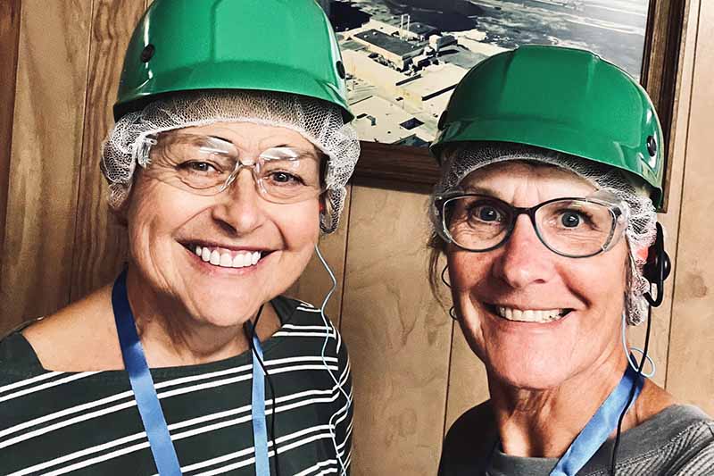 two women wearing green hard hats on tour of Lakeside Foods