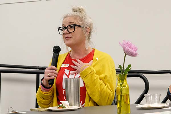 woman wearing yellow sweater holding microphone asking a question