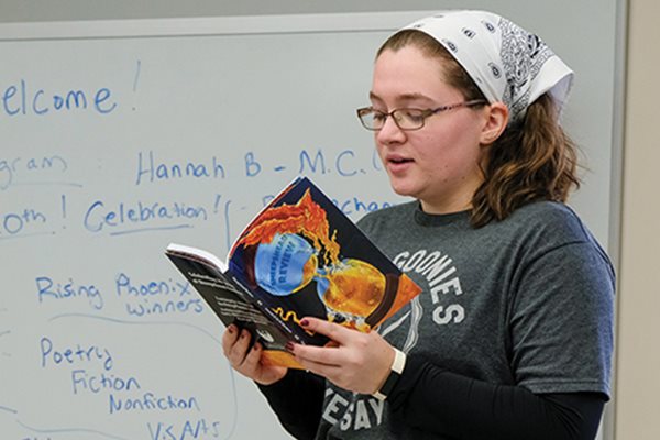 A student reads out-loud in the front of a classroom.