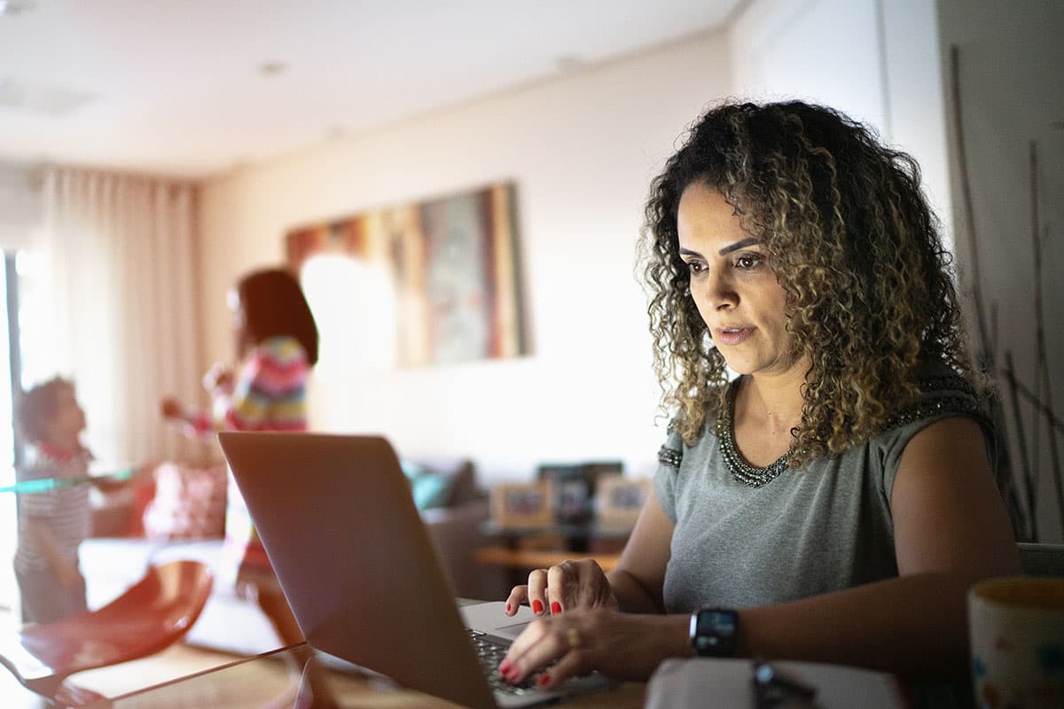 Mother working at home with children in the background