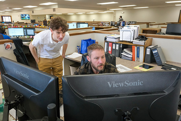 Student working alongside mentor in office cubicle