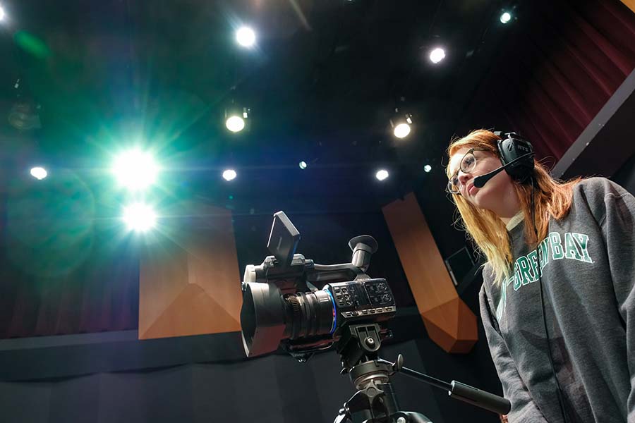 student standing behind camera during video production