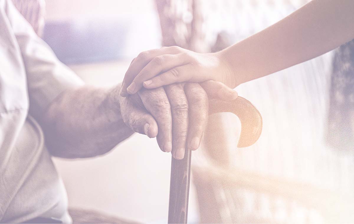 Two hands gently holding—one elderly and one younger—symbolizing care and support
