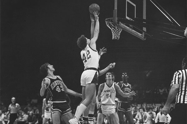UWGB Men's Basketball player jumps to attempt a basket ca. 1970-1979
